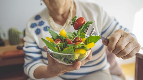 Eine Frau h&auml;lt Sch&uuml;ssel mit Salat in der Hand